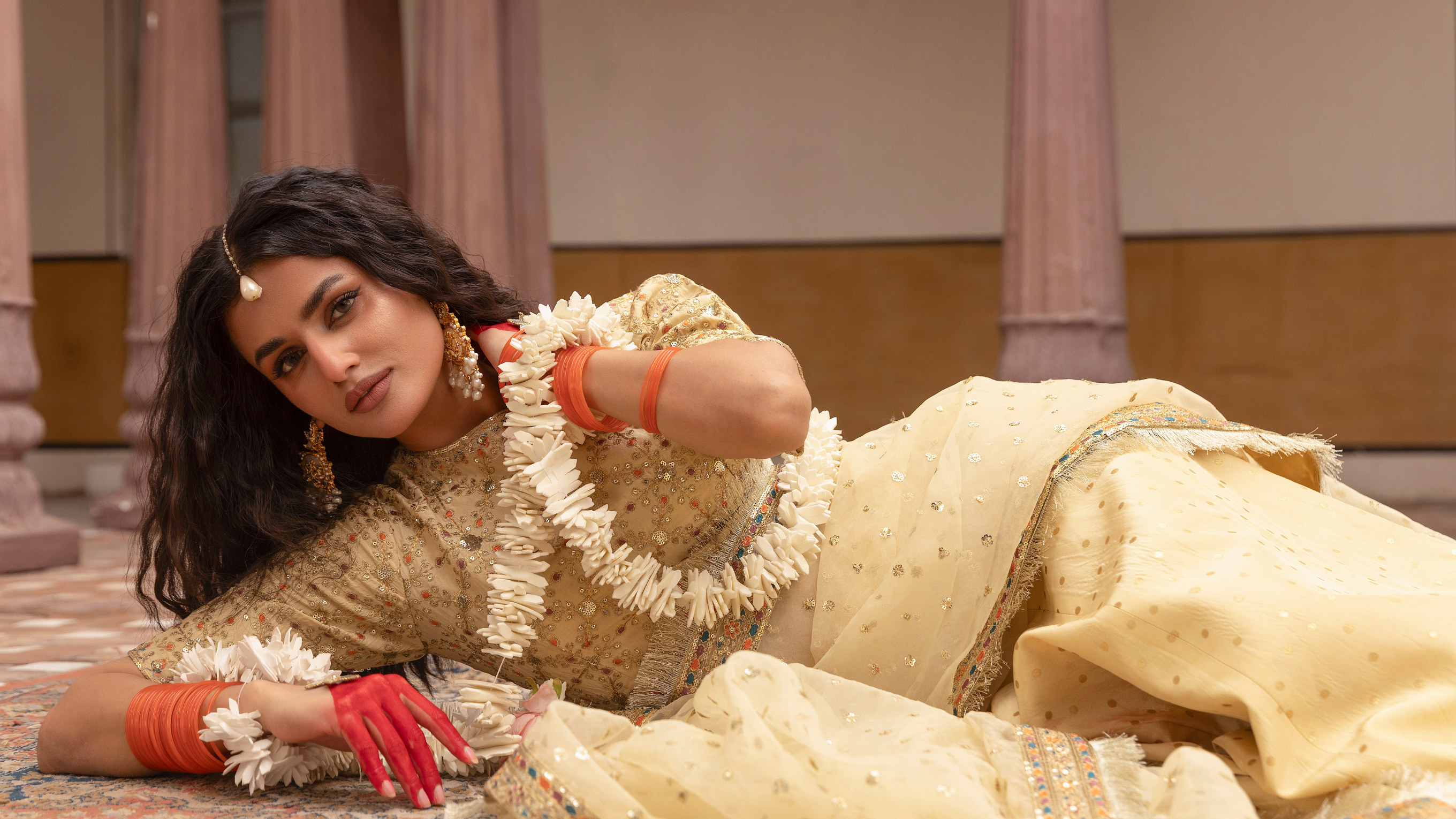 Woman in traditional attire lying on a patterned carpet
