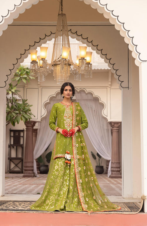 Woman in a green traditional outfit standing in an ornate doorway with chandeliers.